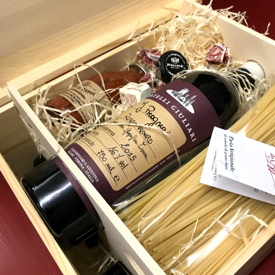 Geöffnete Holzkiste mit Rotwein und Pasta